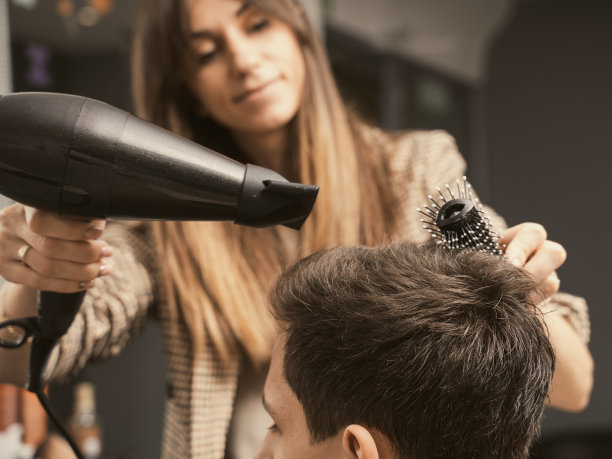 男人的时尚和风格。护发、美容行业、理发师概念。理发店男人的发型。年轻人剪了个现代发型。发廊师傅在理发店为顾客吹干头发图片下载