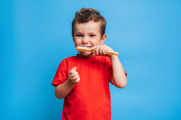 牙齿健康的微笑男孩在蓝色的孤立背景下用牙刷刷牙。口腔卫生。图片下载