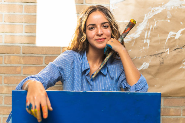 年轻的女画家的肖像正忙于她的工作在车间。爱好与艺术观念图片下载