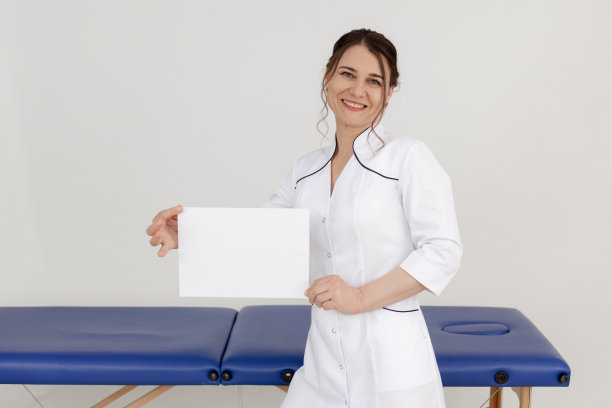 画像中年快乐美丽的女按摩师，医生站在蓝色的沙发附近，拿着一张白纸。图片下载