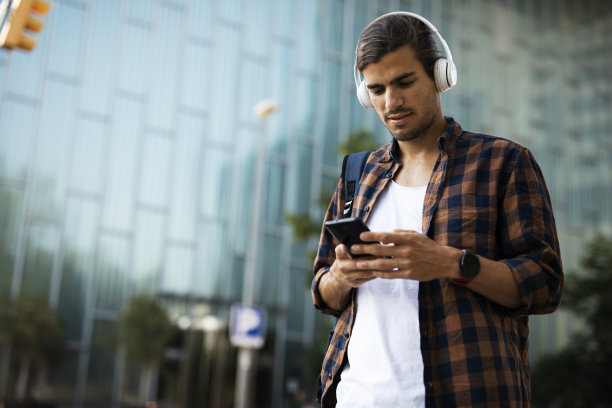 年轻人戴着耳机在外面听音乐。图片下载