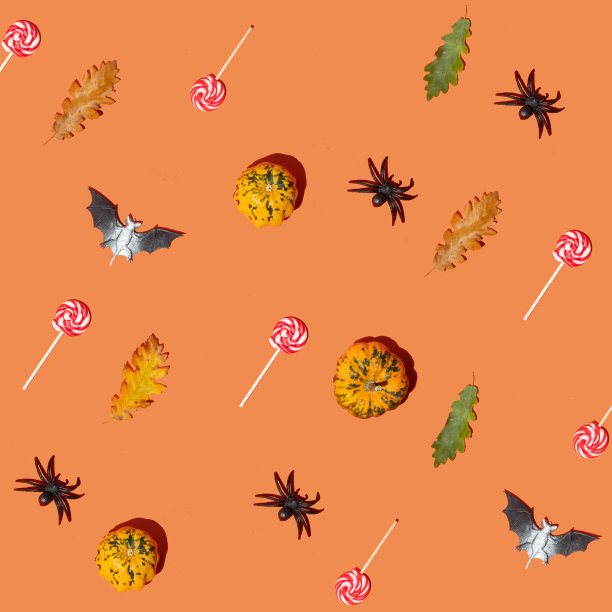 万圣节符号图案组成。橙色背景上的小南瓜，秋叶，赌注，蜘蛛和糖果。简约的概念。图片下载