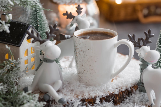 一张有可爱驯鹿的圣诞卡和一杯以美丽的焦景为背景的热咖啡。新年静物画。家庭度假的概念，温馨和舒适。图片下载
