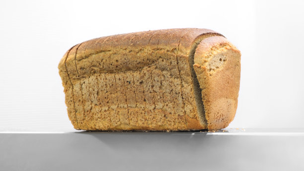 切片机中的面包，超市中的工业面包切片机，带有面包屑，可随时使用。图片下载