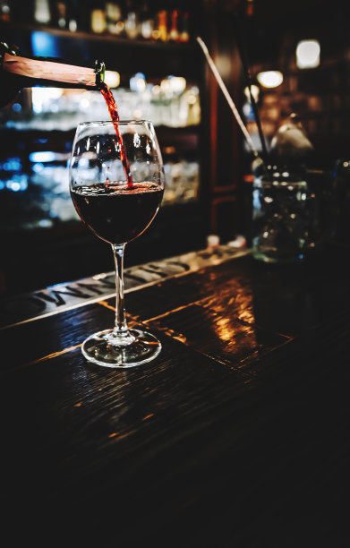 在咖啡馆或酒吧里，调酒师把红酒倒进玻璃杯里图片下载