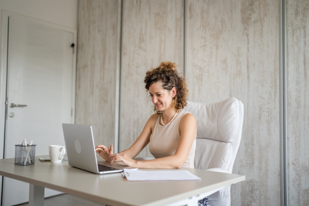 一个年轻的女商人回到办公室用笔记本电脑工作图片下载