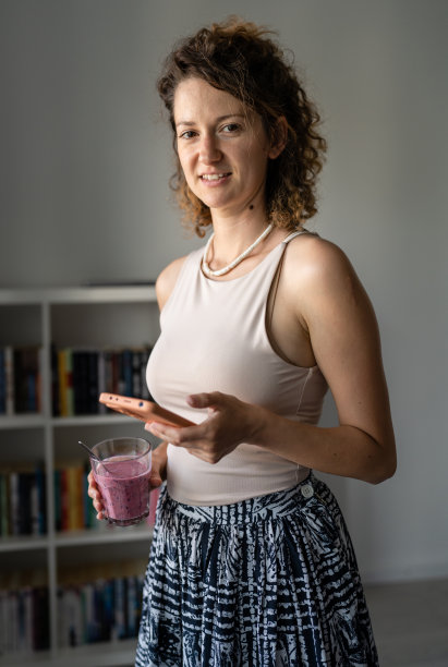 一位女士站在办公室里喝奶昔，用手机图片下载