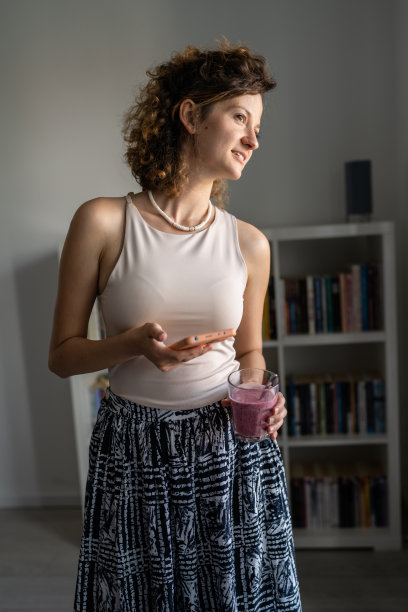 一位女士站在办公室里喝奶昔，用手机图片下载