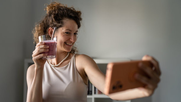 一个女人站在办公室里一边喝着冰沙一边打视频电话图片下载