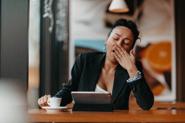 一个昏昏欲睡的女人在休息时间坐在咖啡馆里用平板电脑。经营理念。图片下载