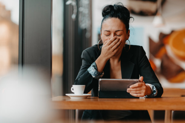 一个昏昏欲睡的女人在休息时间坐在咖啡馆里用平板电脑。经营理念。图片下载