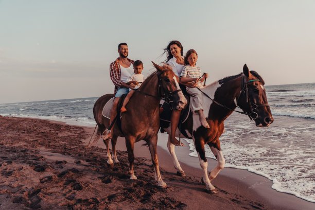 一家人和孩子们一起在沙滩上骑马。有选择性的重点图片下载