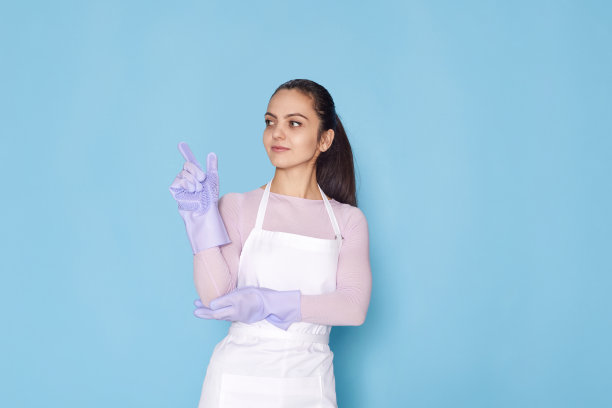 戴着紫色橡胶手套和围裙的女人举起食指图片下载
