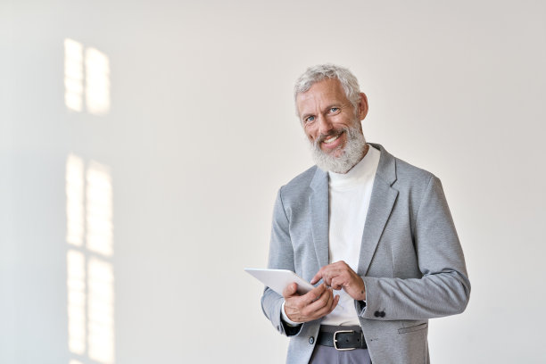 微笑的老老年商人使用平板隔离在白色背景。图片下载