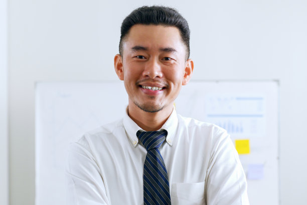 画像年轻的亚洲商人工作在正式的西装看着相机和微笑图片下载