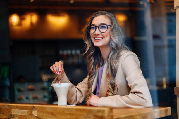 商业女性坐在咖啡馆的窗户后面等待商业伙伴图片下载