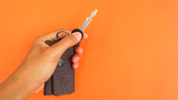 手握钥匙在橙色背景，人体部分的概念图片下载