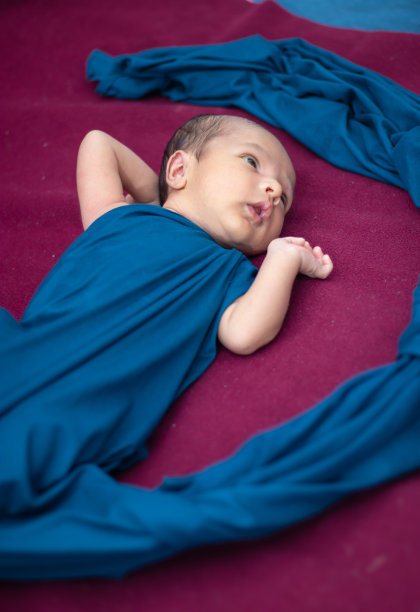 刚出生的宝宝躺在红色丝绒布上，从不同角度看表情可爱图片下载