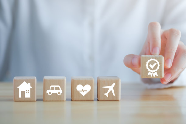 保险的概念。对可能发生的情况的保护。手持质量保证与房屋，汽车，医疗保健和旅游图标在木块保证安全和保证生活理念。图片下载
