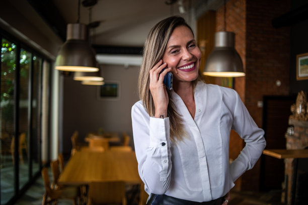 一位女商人站在餐厅里用手机图片下载