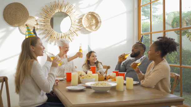 一个多民族的群体。白人和非裔美国黑人家庭画像，妇女在假日聚会在家里举行庆祝晚宴。人们的生活方式。团聚。图片下载