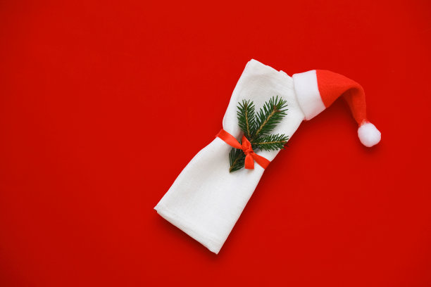 白色餐巾纸和红色背景的圣诞老人帽。图片下载