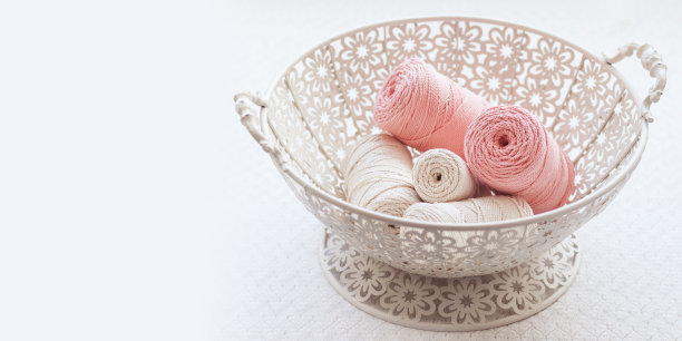 手工编织流苏和棉线在篮子上的白色背景。用棉线编织的绳子和绳子绑在铁丝篮上。用于编织、工艺品横幅、广告等。关闭了。本空间图片下载