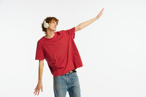 梦想中的年轻人，穿着红色t恤的学生，耳机被隔离在白色背景上。情感，面部表情，青春，音乐的概念图片下载