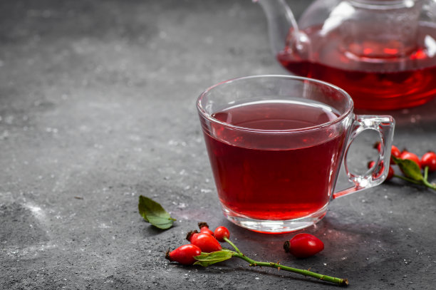 玫瑰果玻璃杯草药茶与玫瑰果在乡村的桌子上。狗狗冬茶背景图片下载