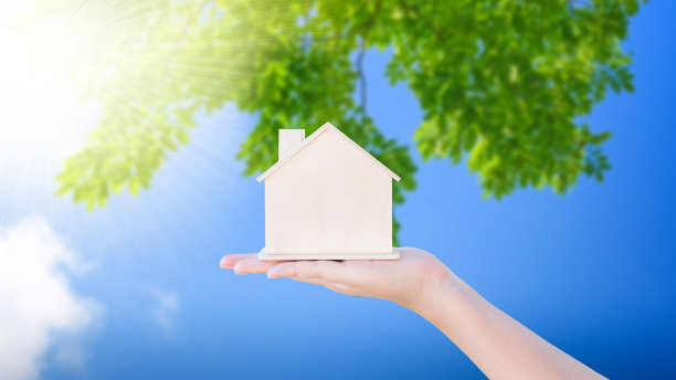 女人手握小木屋模型与自然绿色抽象背景。家庭生活和商业地产理念，生态住宅图片下载