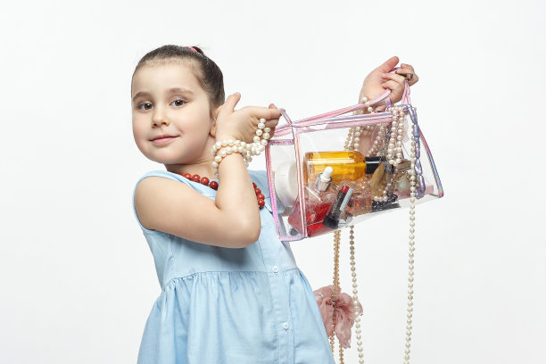 小黑头发的时尚达人手里拿着一包化妆品。有趣的照片拍摄的女孩在工作室的白色背景图片下载