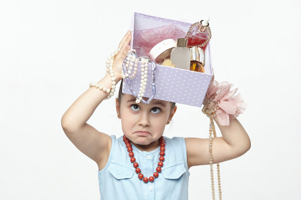 小黑头发时尚达人手里拿着一盒化妆品。一个女孩在摄影棚里用白色背景拍的有趣照片图片下载