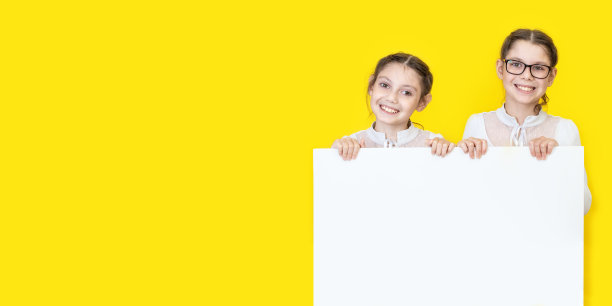 女孩姐妹拿着白色的空海报，微笑着。举着白色广告牌的女孩图片下载