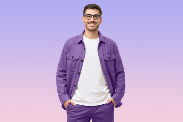 年轻男子站着，双手插在口袋里，穿着休闲的紫色衬衫，看着相机图片下载