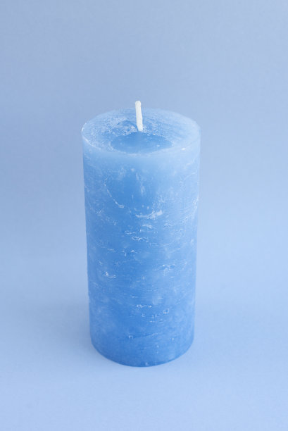 一个大的蓝色新蜡蜡烛室内设计的蓝色背景。简约美观的配饰。为寒冷的冬天礼物和装饰家庭，咖啡馆，商店的想法。放松和冥想的氛围图片下载