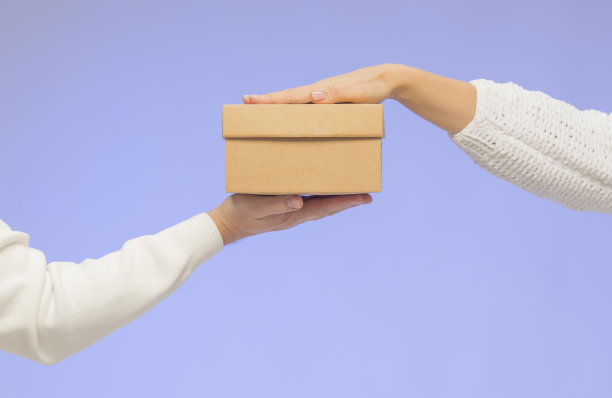 双手捧着礼品盒孤立无援。蓝色背景上，男女两手分别拿着礼品盒。圣诞购物礼物概念图片下载