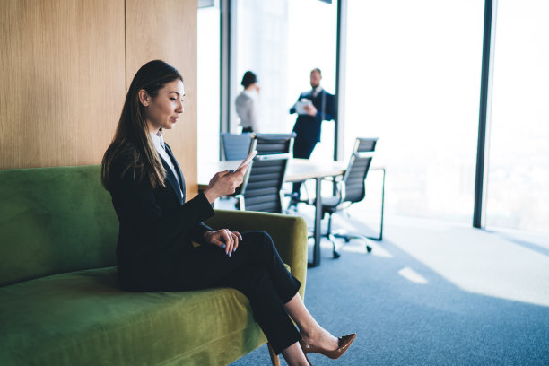 自信的民族经理带着智能手机坐在沙发上休息图片下载