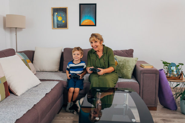 奶奶和孙子在家里玩电子游戏，而他们的狗坐在他们旁边图片下载
