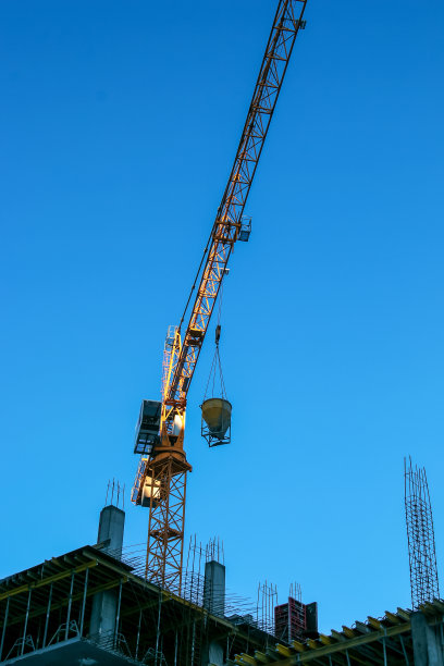 蓝蓝的天空衬托着建筑起重机。房地产行业。起重机在建筑工地使用起重设备。图片下载