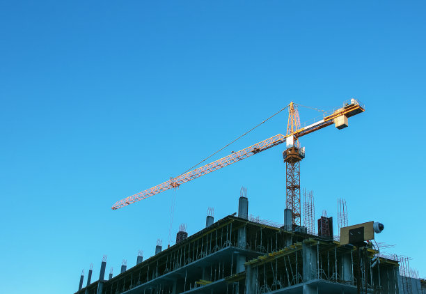 蓝蓝的天空衬托着建筑起重机。房地产行业。起重机在建筑工地使用起重设备。图片下载