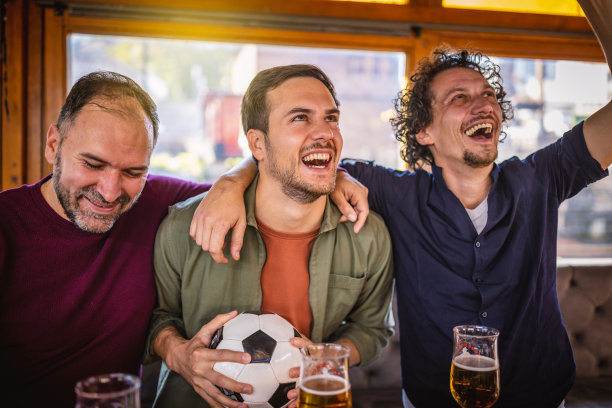 兴奋的体育迷们一边在酒吧里观看比赛，一边为自己的球队加油图片下载