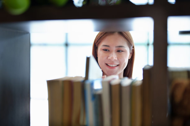 一位年轻的亚洲妇女在图书馆寻找知识时表现出的喜悦图片下载