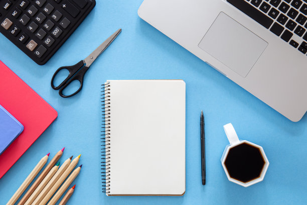 平铺，记事本，笔记本电脑和文具在蓝色的背景。图片下载