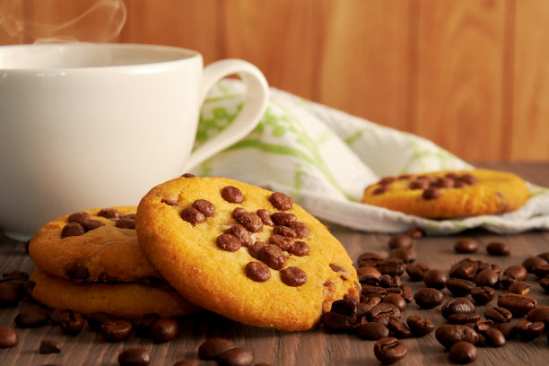 咖啡杯，热蒸汽，巧克力饼干和咖啡。木桌上的谷物图片下载