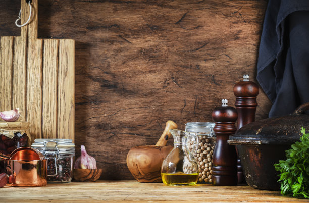 烹饪食物背景:乡村木厨房桌，铸铁锅，香料研磨机，砧板，香料和调味料，储物罐。本空间图片下载