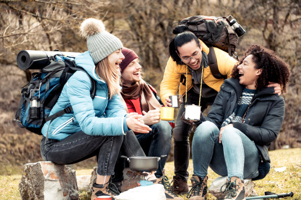 快乐的多种族朋友坐在喝咖啡后，一天的徒步旅行在山-旅行者露营在森林和放松在一起-冒险徒步度假的概念图片下载