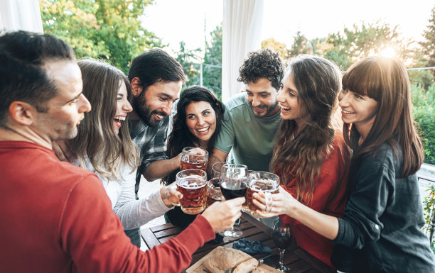 一群快乐的年轻人在餐厅酒吧喝酒喝酒-夕阳下露台聚会上微笑的朋友-青春和友谊的概念图片下载