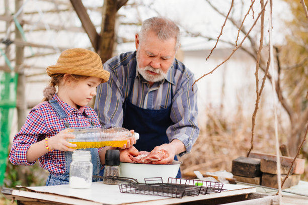 孙女帮爷爷做烤肉，把葵花籽油浇在肉上图片下载
