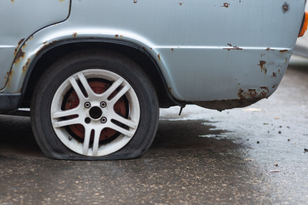 一辆生锈的旧车，后轮被戳破了图片下载