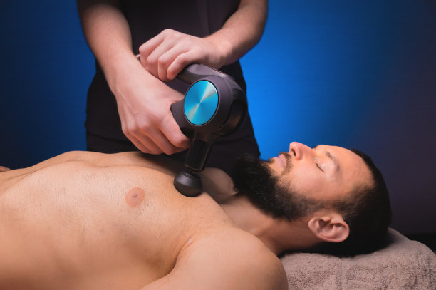 健身房医务室的运动打击乐按摩。按摩师做按摩练习。敲击疗法再生运动身体按摩。运动损伤康复的概念。图片下载